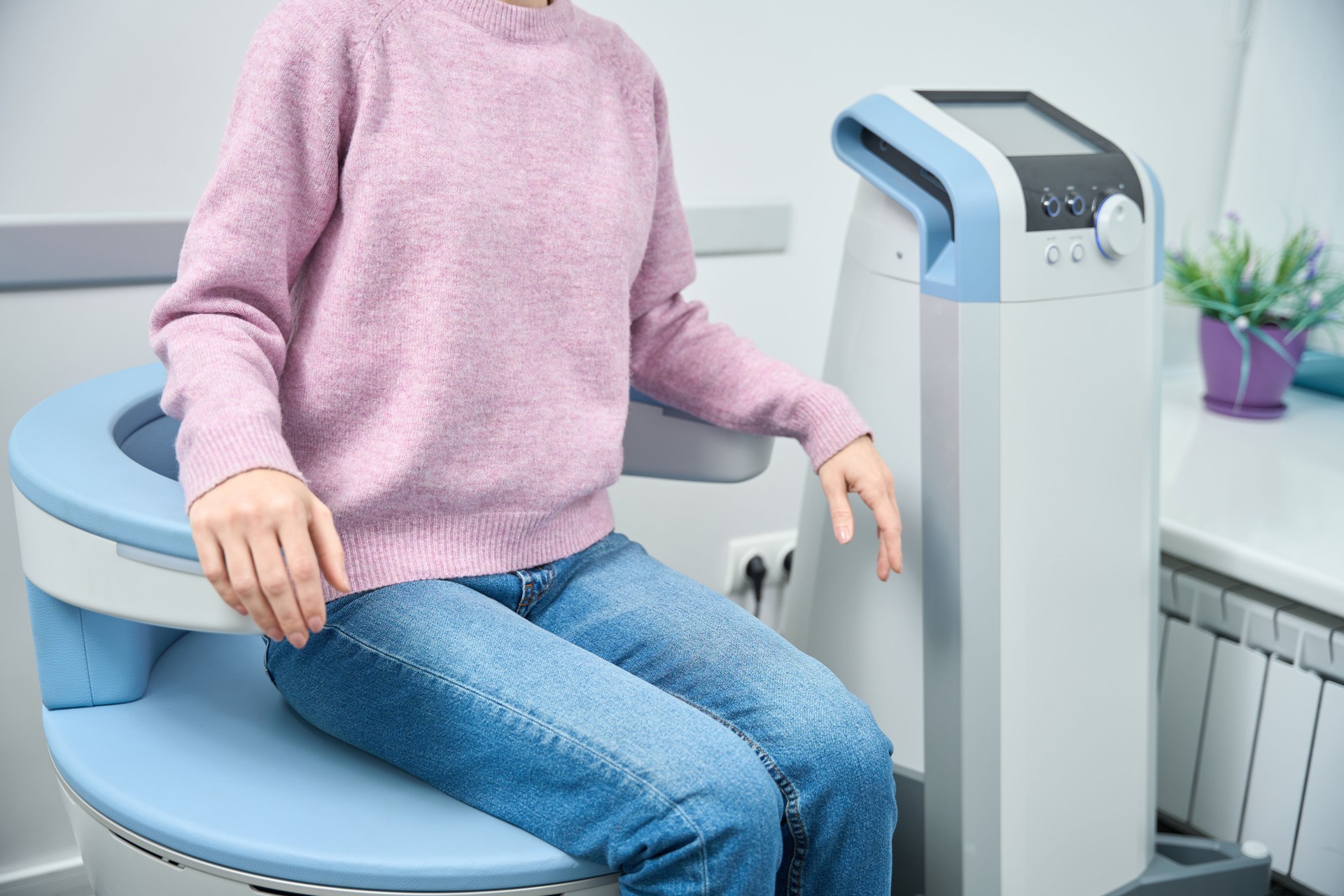 Woman sitting on electromagnetic stimulation chair medical clinic